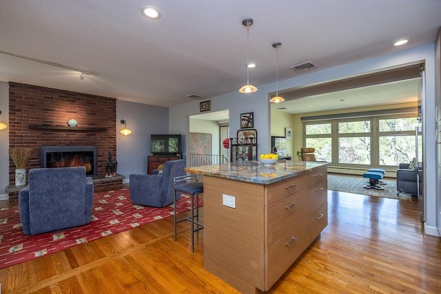 kitchen featuring stone counters, visible vents, light wood-style flooring, and open floor plan