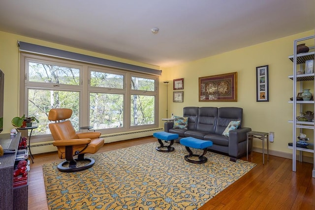 living room with a baseboard heating unit, a healthy amount of sunlight, and wood finished floors