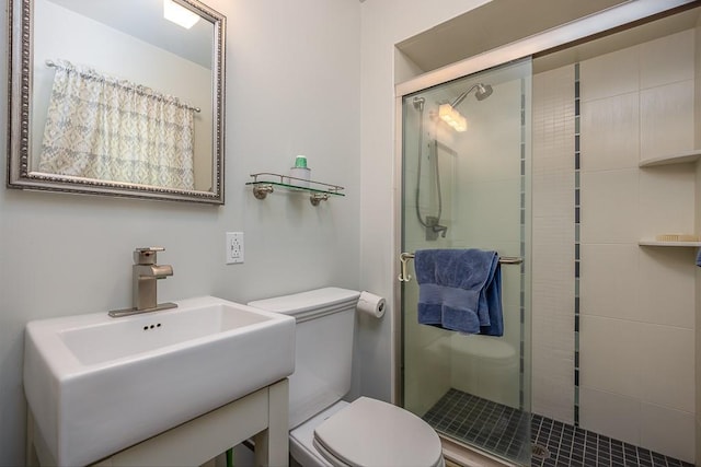 bathroom featuring a sink, a stall shower, and toilet