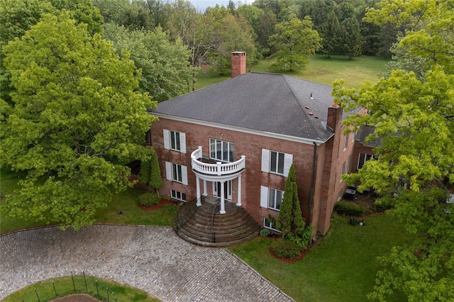 view of front of home with brick siding, a front lawn, and a chimney