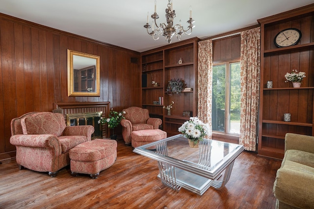 living area with wood walls, built in features, ornamental molding, wood finished floors, and a notable chandelier
