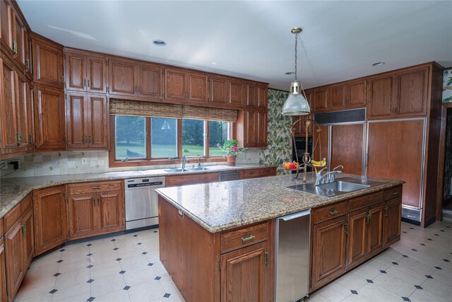 kitchen with stainless steel dishwasher, brown cabinetry, a sink, and light floors