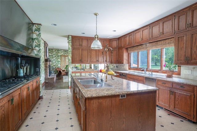kitchen with a sink, pendant lighting, a center island with sink, and brown cabinets