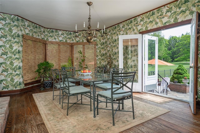 dining area featuring crown molding, wallpapered walls, an inviting chandelier, and hardwood / wood-style flooring