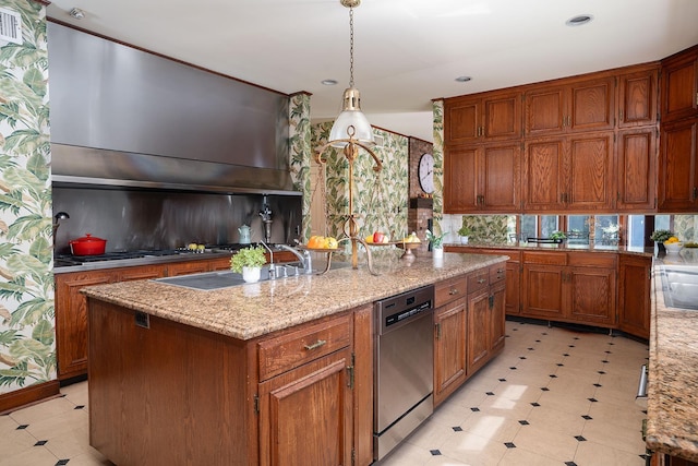 kitchen featuring light stone countertops, brown cabinetry, an island with sink, stainless steel appliances, and pendant lighting