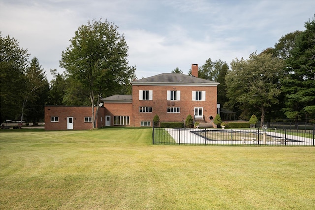 back of property featuring a yard, brick siding, fence, and a chimney