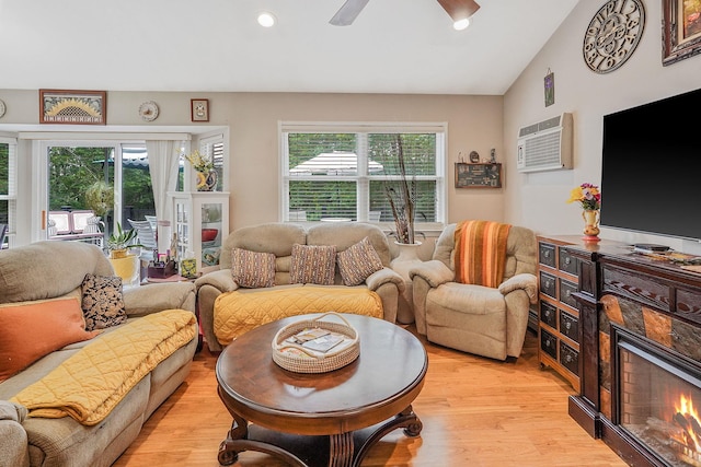 138 Barton Ave, Patchogue, NY 11772 - living area with an AC wall unit, light wood finished floors, a warm lit fireplace, ceiling fan, and vaulted ceiling