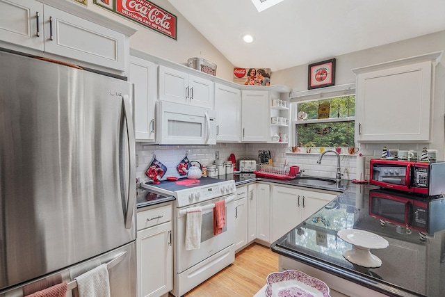 138 Barton Ave, Patchogue, NY 11772 - kitchen with white appliances, tasteful backsplash, dark countertops, vaulted ceiling, and white cabinets