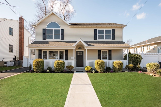 traditional home featuring a front lawn, fence, and covered porch