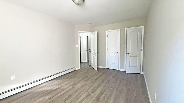 unfurnished bedroom with baseboards, a baseboard radiator, and wood finished floors
