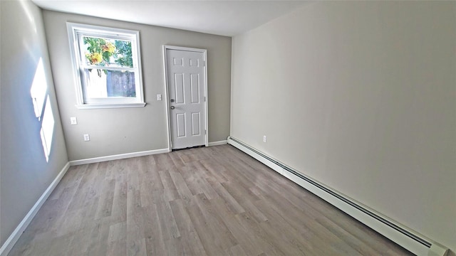 unfurnished room with light wood-style floors, a baseboard radiator, and baseboards