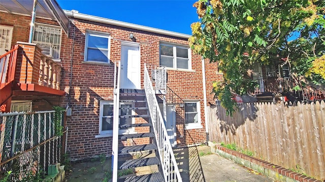 back of house featuring fence and brick siding