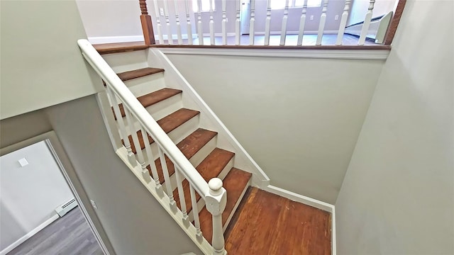 staircase with baseboard heating and wood finished floors