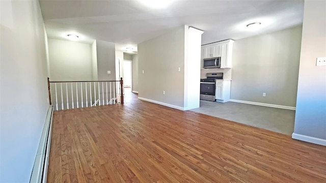 unfurnished room with baseboards, baseboard heating, and wood finished floors