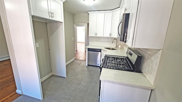 kitchen with decorative backsplash, white cabinetry, light stone counters, a sink, and stainless steel appliances