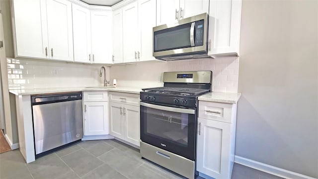 kitchen with backsplash, stainless steel appliances, white cabinetry, and a sink
