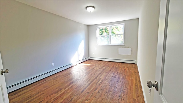 unfurnished room with a baseboard heating unit and wood finished floors