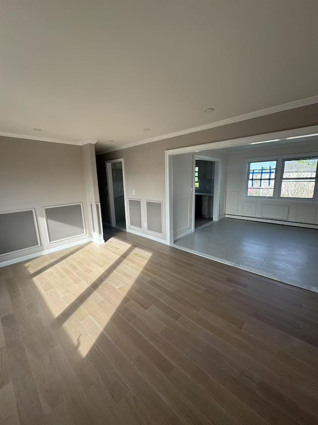 unfurnished living room with ornamental molding, a decorative wall, and wood finished floors