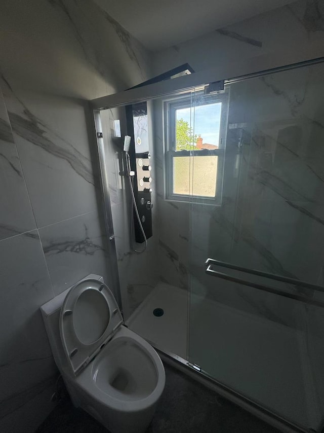 bathroom with a marble finish shower and toilet