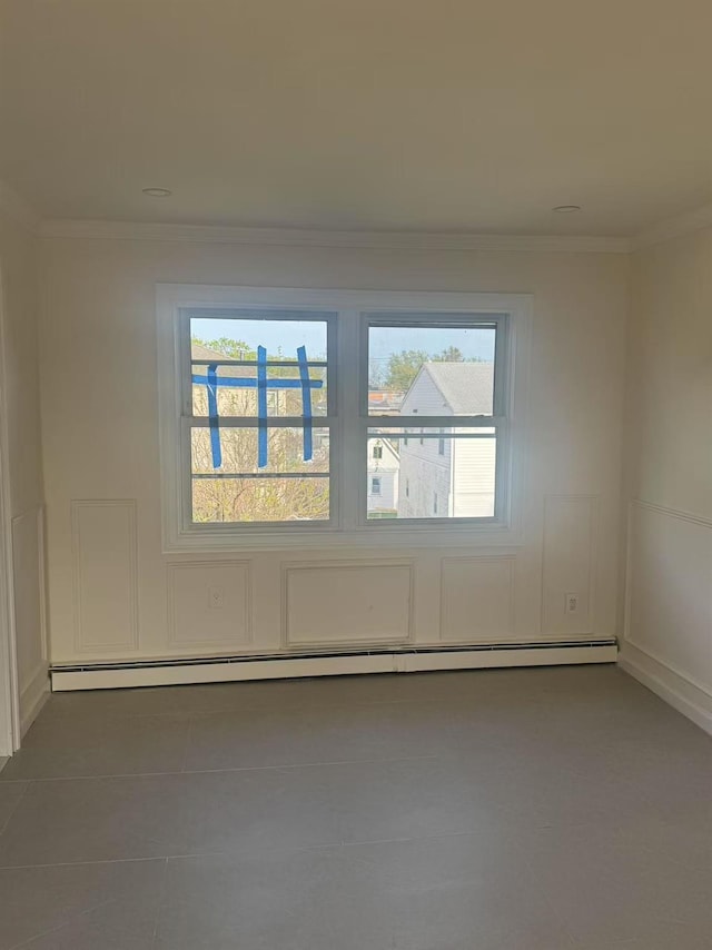 spare room with tile patterned floors, ornamental molding, and a baseboard heating unit