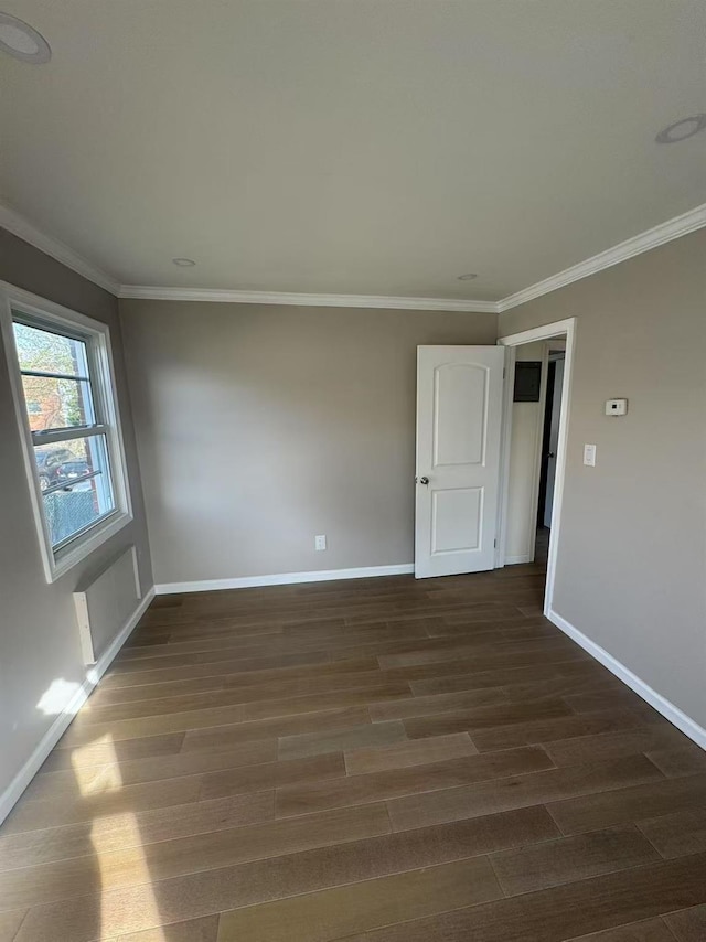 unfurnished room with crown molding, baseboards, and dark wood finished floors