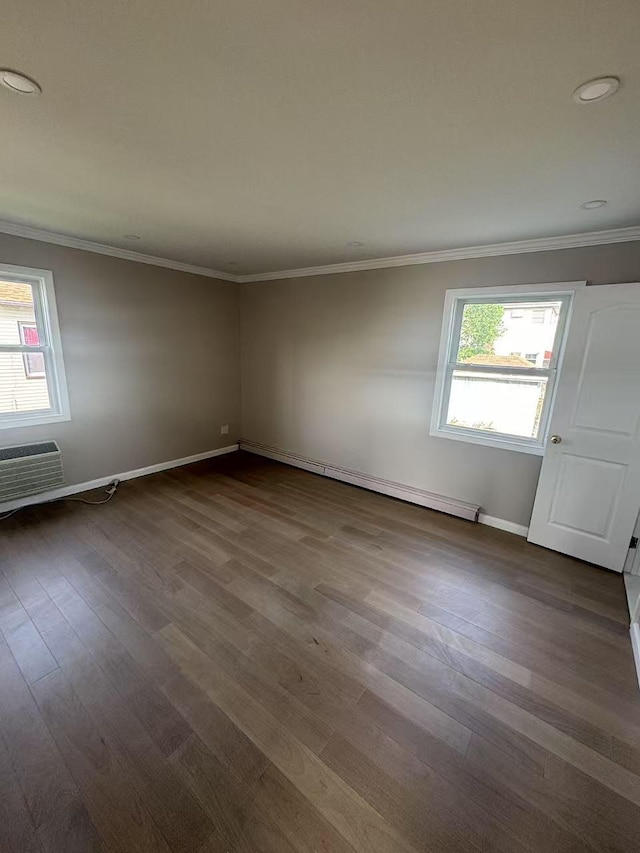 spare room featuring crown molding, dark wood finished floors, baseboards, and a healthy amount of sunlight