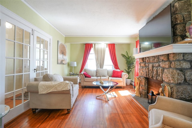 living room featuring wood-type flooring, ornamental molding, and a stone fireplace