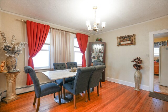 dining space featuring wood-type flooring, a chandelier, plenty of natural light, and ornamental molding