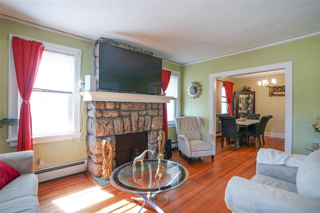 living room featuring crown molding, a fireplace, wood finished floors, a baseboard radiator, and a chandelier