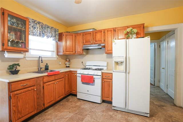 kitchen featuring a sink, light countertops, under cabinet range hood, and white appliances