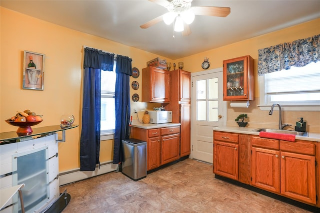 kitchen with ceiling fan, baseboard heating, a sink, light countertops, and white microwave