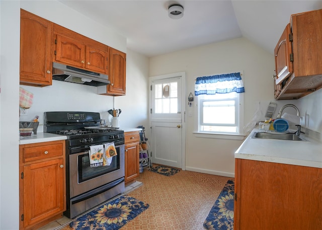 kitchen featuring stainless steel gas range, under cabinet range hood, a sink, and light countertops