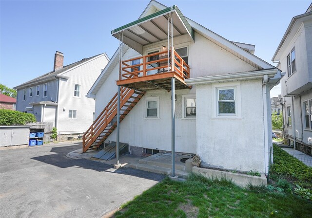 rear view of house featuring a wooden deck, stairs, stucco siding, and a patio