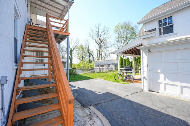 exterior space with stairs, a garage, a wooden deck, and fence