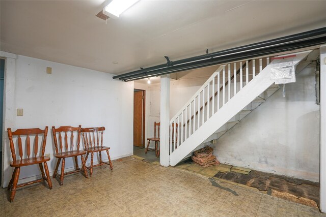 finished below grade area featuring tile patterned floors and stairway