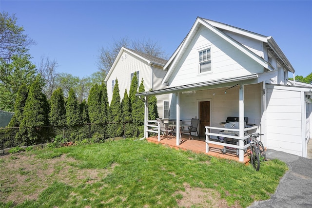 back of property with a lawn, fence, and a wooden deck
