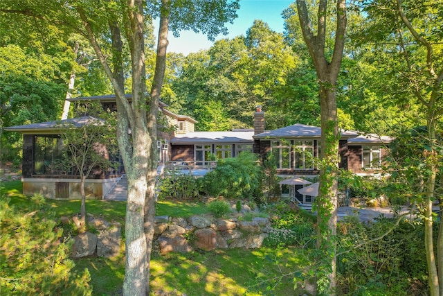 back of property with a chimney and a sunroom