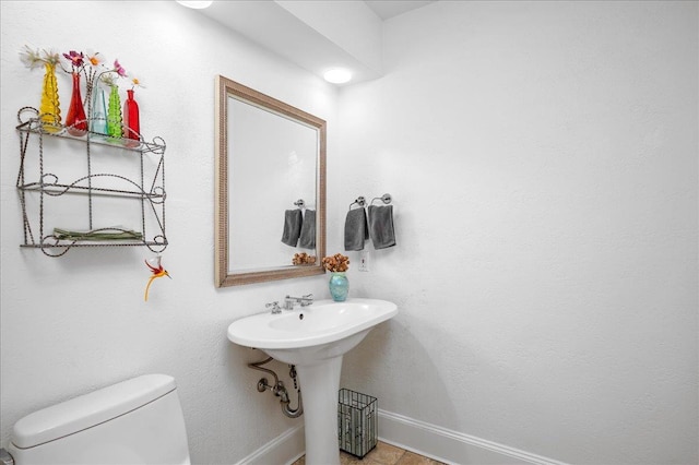 bathroom featuring baseboards, a sink, and toilet
