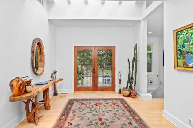 foyer with baseboards, french doors, wood finished floors, and visible vents