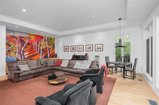 living area featuring recessed lighting, a tray ceiling, visible vents, and wood finished floors