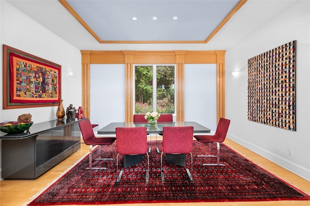 dining space with baseboards, wood finished floors, and a tray ceiling