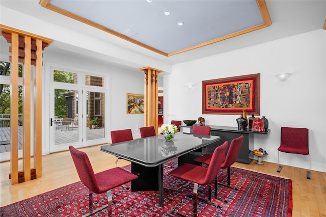 dining room featuring decorative columns, wood finished floors, recessed lighting, a raised ceiling, and french doors