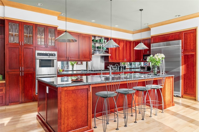 kitchen featuring light wood-style flooring, decorative light fixtures, dark brown cabinets, and stainless steel appliances