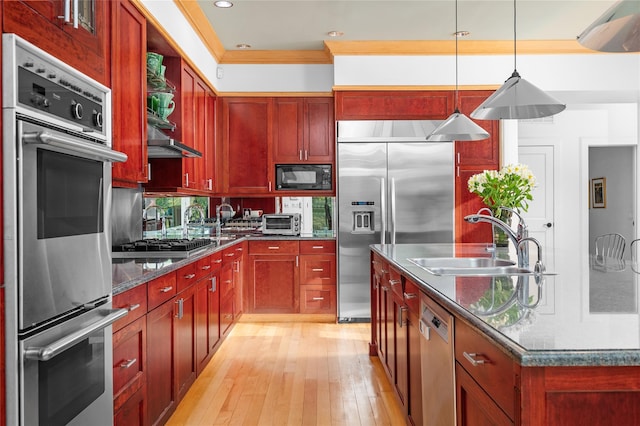 kitchen featuring reddish brown cabinets, a sink, light wood finished floors, and built in appliances