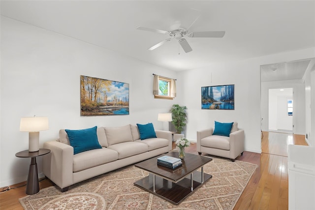 living area with baseboards, a ceiling fan, and wood finished floors