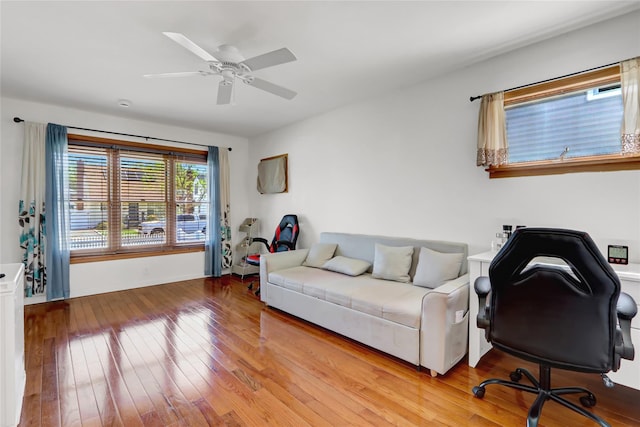 living room featuring baseboards, wood-type flooring, and a ceiling fan