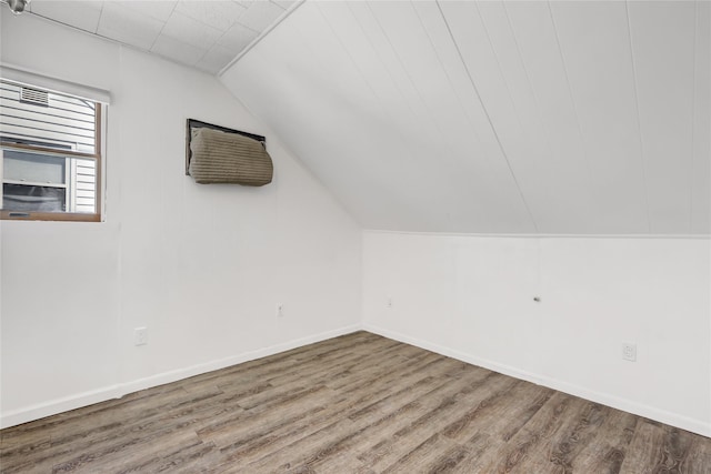 additional living space featuring baseboards, wood finished floors, and vaulted ceiling