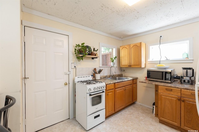 kitchen with white gas stove, stainless steel microwave, brown cabinets, a sink, and backsplash