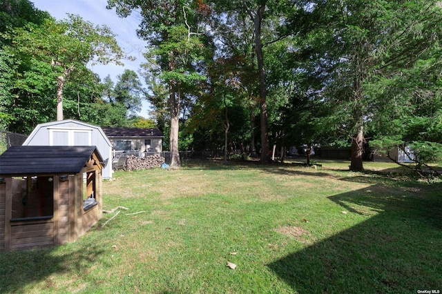 view of yard featuring a storage shed, fence, and an outdoor structure