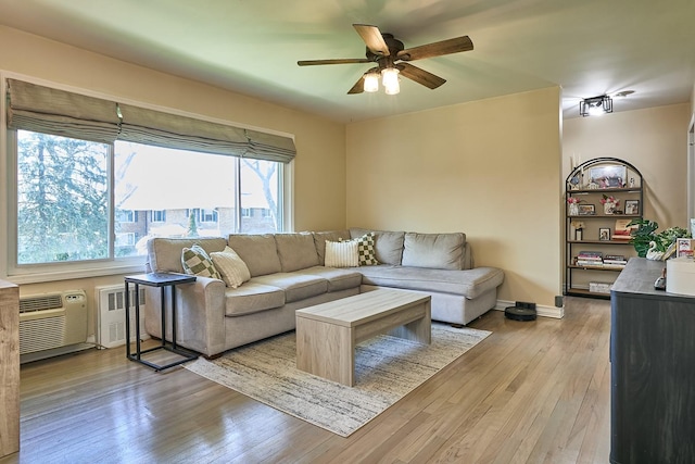 living room featuring a ceiling fan, baseboards, and light wood-style flooring